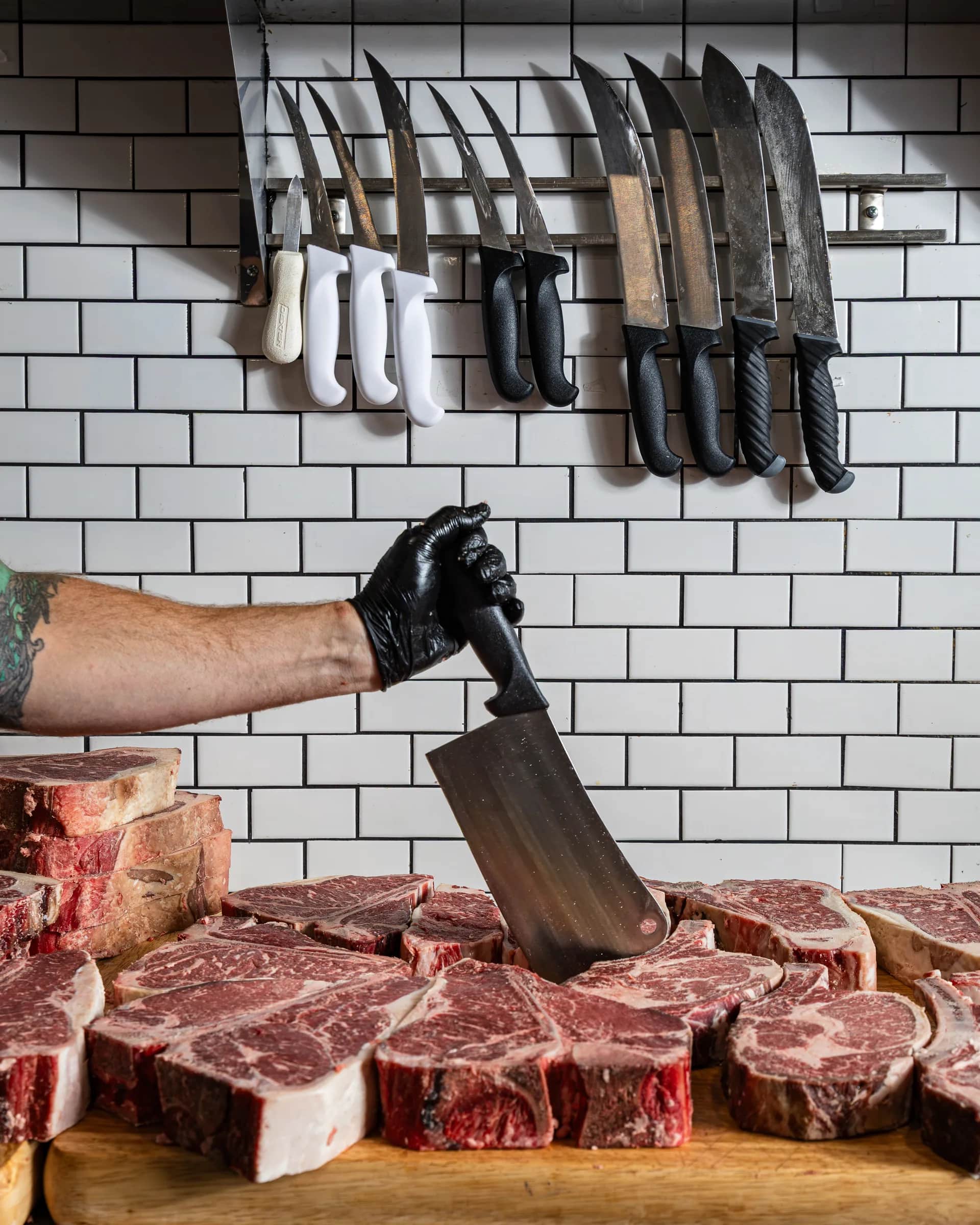 Cleaver planted in a Prime ribeye beneath the knife rack