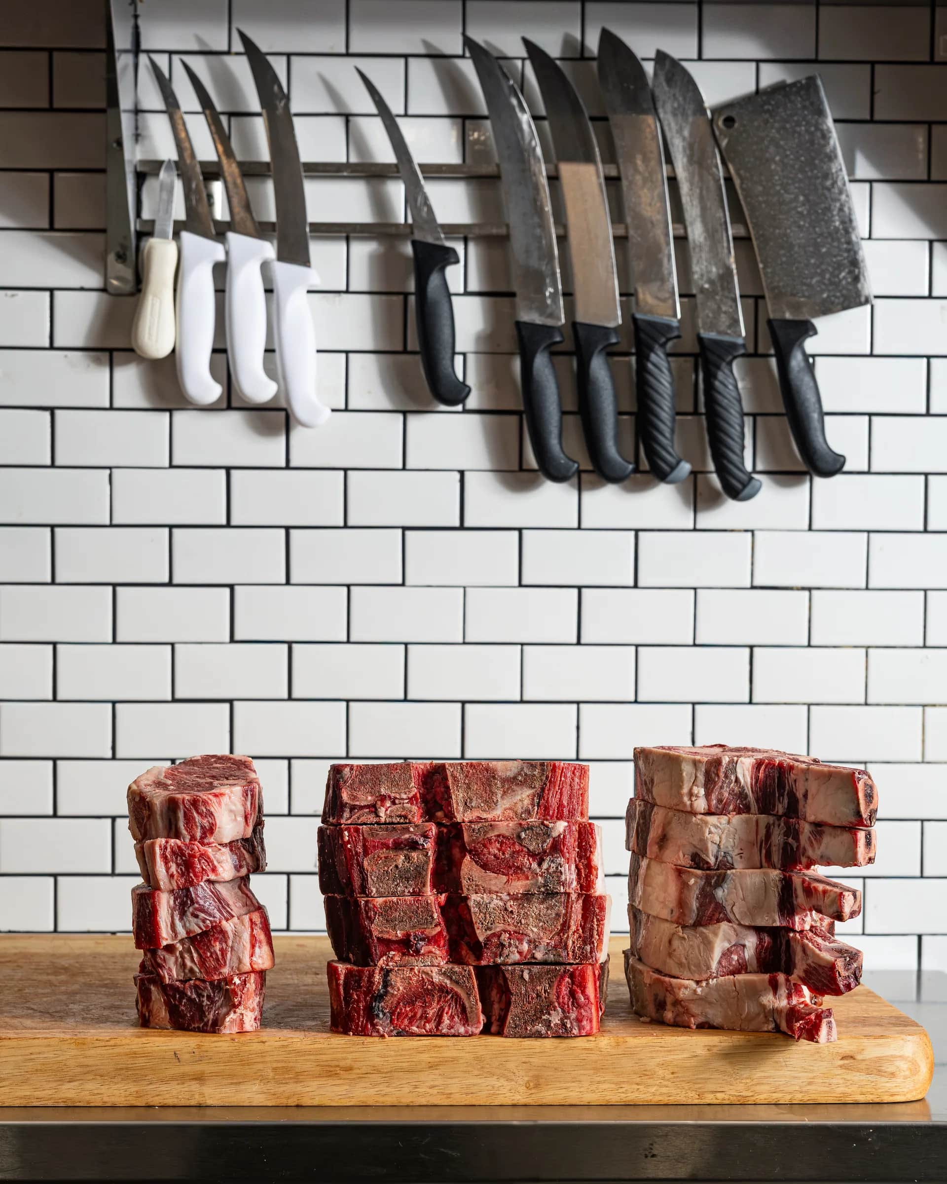 Three stacks of steaks below the knife rack