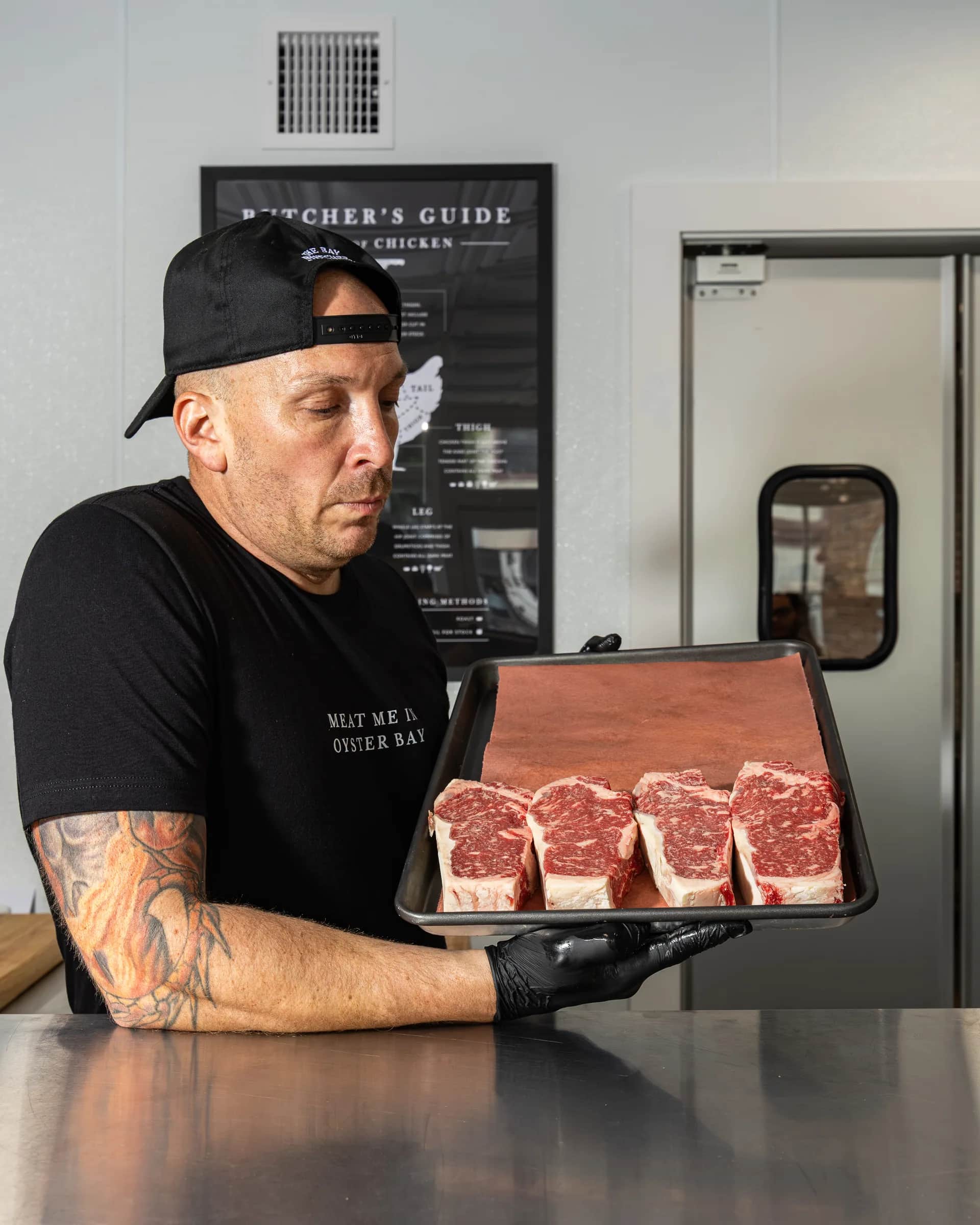 Butcher presenting a tray of prime ribeye steaks