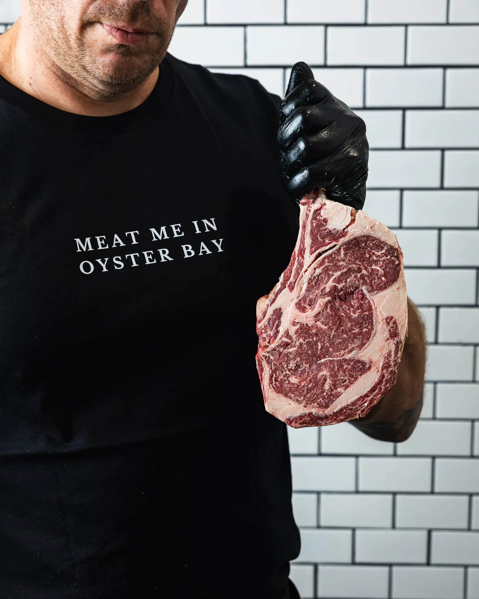 Meat Me In Oyster Bay tee holding a prime ribeye